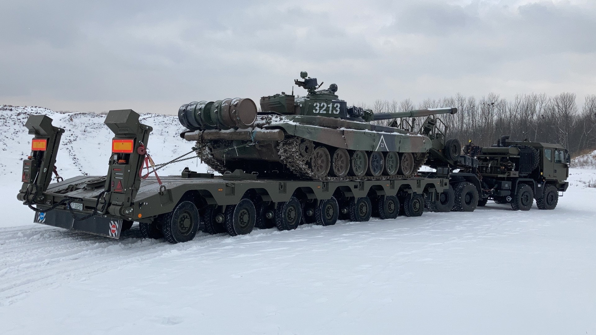 Cama baja militar transportando vehículo blindado.